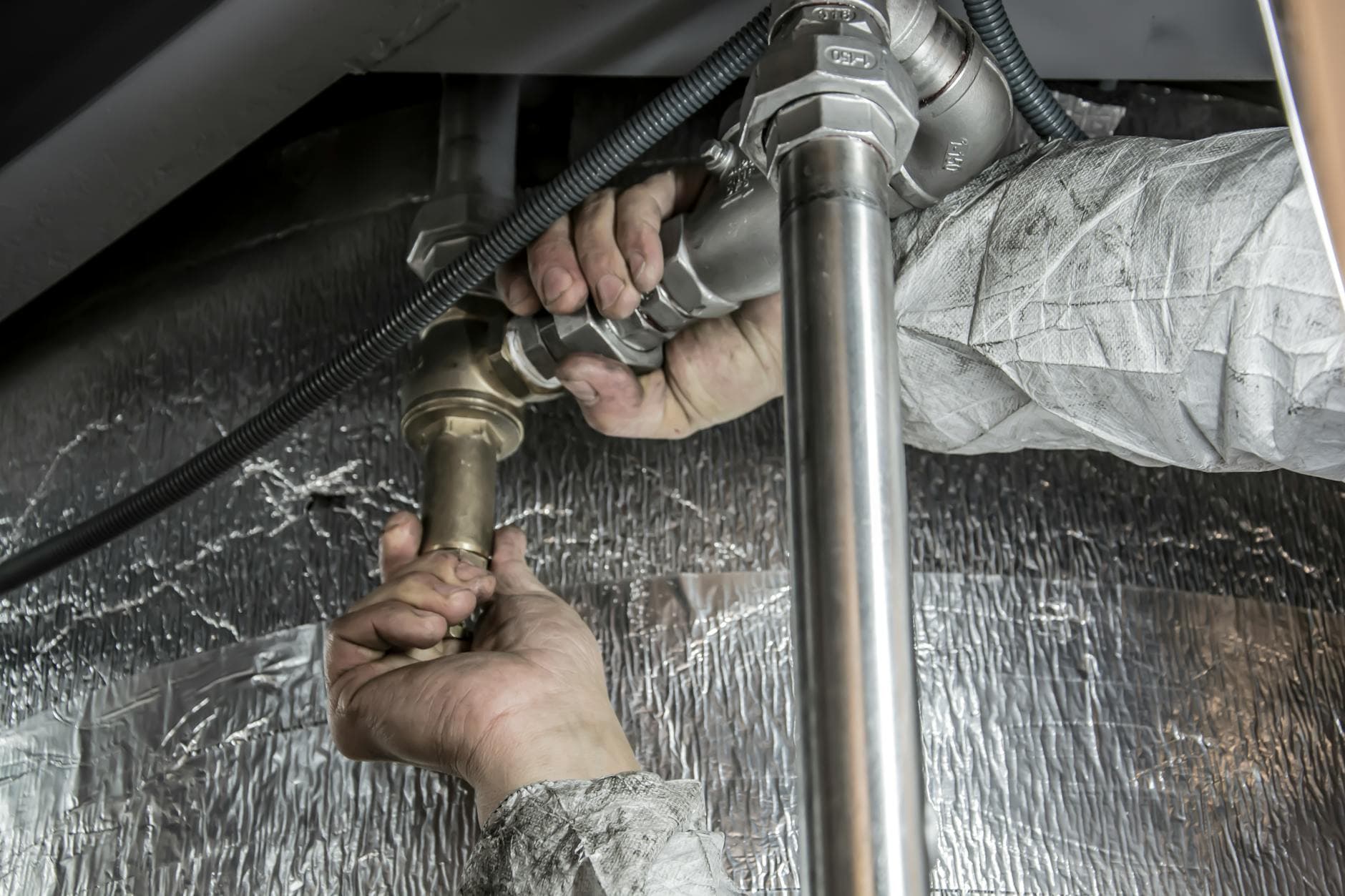 Plumber working under a kitchen sink in a residential home