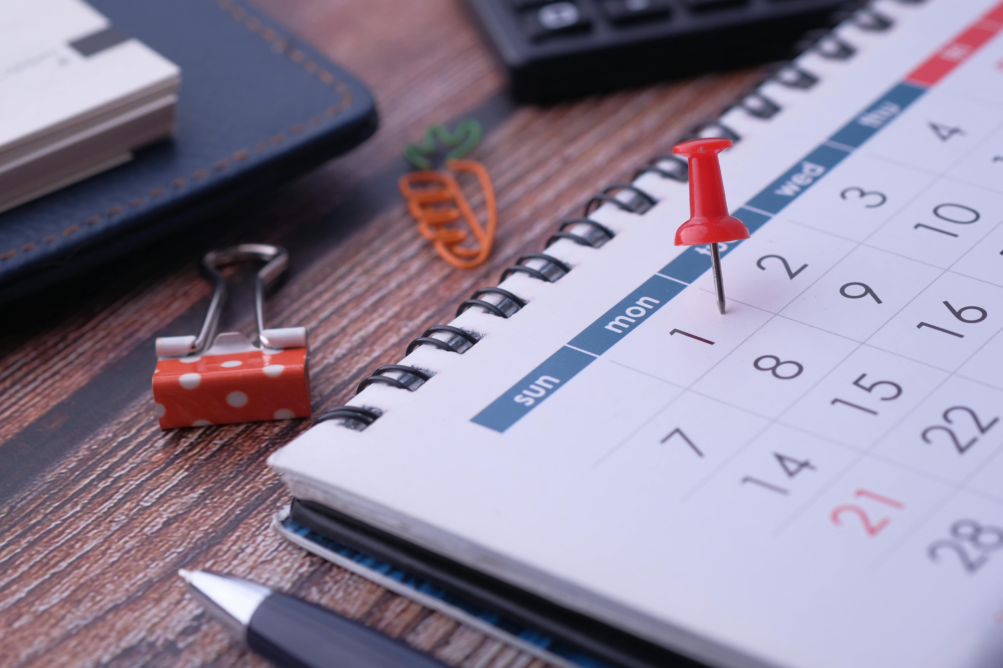 Calendar with weekly lawn care service dates marked next to a coffee cup in soft morning light